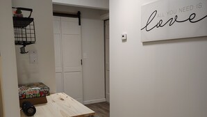 A hallway with a white door, a wall-mounted sign saying 'ALL YOU NEED IS love', and a small shelf with a box of Deer Pong. - Near Kentucky lake Running bear cottage ! (Gilbertsville)