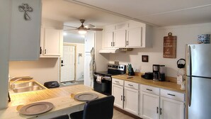 A modern kitchen with white cabinets, a wooden countertop, a black chair, a stainless steel refrigerator, and a ceiling fan. - Near Kentucky lake Running bear cottage ! (Gilbertsville)