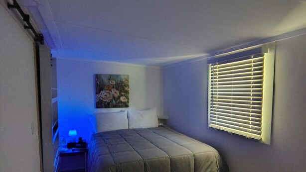 A bedroom with a bed, a painting on the wall, and a window with blinds. - Near Kentucky lake Running bear cottage ! (Gilbertsville)