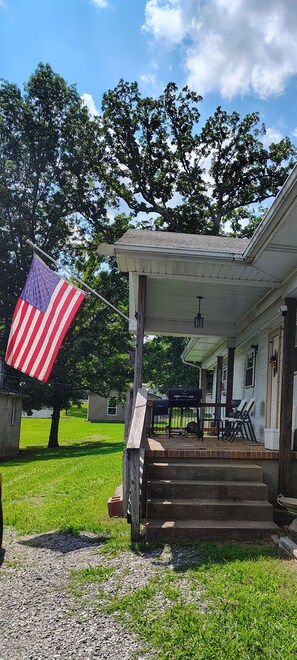 Ein Haus mit einer Veranda und einer Treppe zum Eingang, sowie eine amerikanische Flagge.