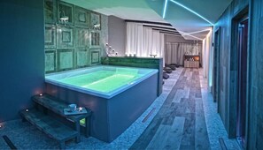 Une salle de bain moderne avec une grande baignoire, des bancs en bois et une coiffeuse avec un miroir.