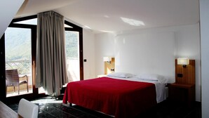 A hotel room with a bed, two bedside lamps, a window with a view, and a door leading to an outdoor area. - Vea Resort Hotel (Mercato San Severino)