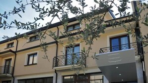 A multi-story building with balconies, large windows, and a sign with a logo. - Vea Resort Hotel (Mercato San Severino)