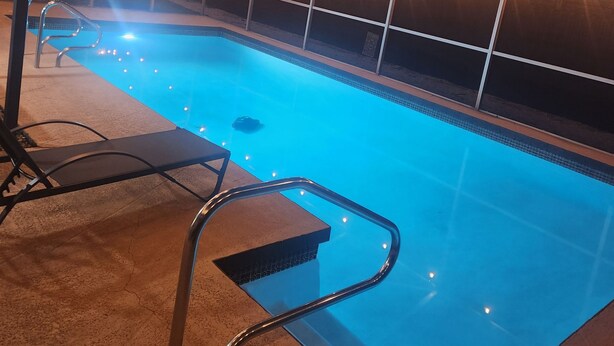 Piscina interna com área coberta, escada de metal e luzes de corda.