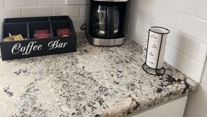 Uma cozinha com cafeteira, placa de café e suporte para canecas com frases motivacionais.
