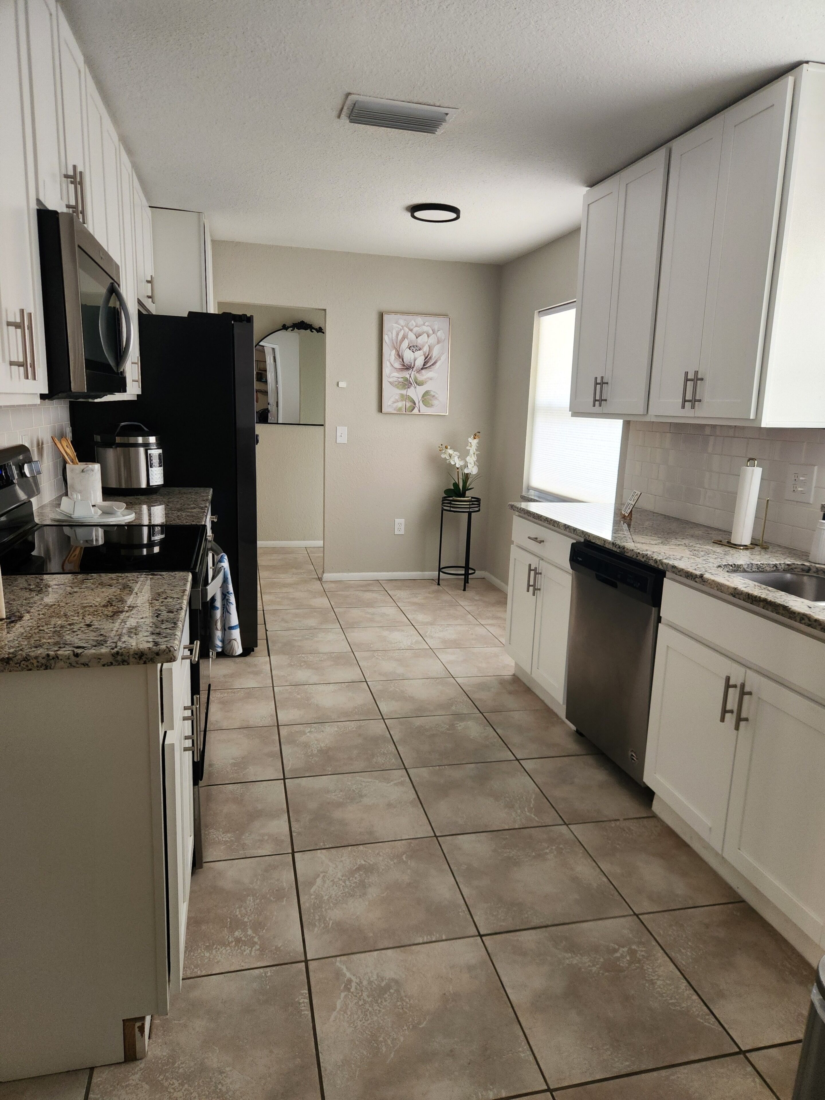 A kitchen with white cabinets, a black refrigerator, a stainless steel stove, and a dishwasher.