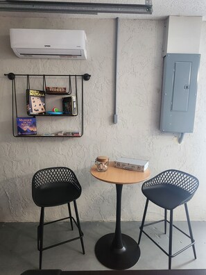 Ein Zimmer mit einem runden Tisch, zwei Stühlen, einem Bücherregal und einer Klimaanlage.