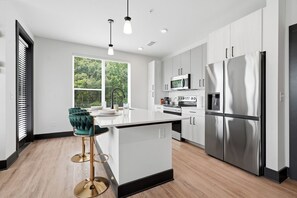 A modern kitchen with white cabinetry, stainless steel appliances, and a bar stool.