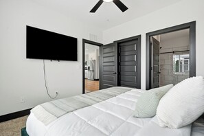 A bedroom with a bed, a television mounted on the wall, and a door leading to a bathroom.