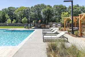 A swimming pool with lounge chairs and a barbecue area.