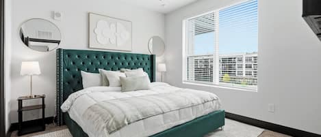 A bedroom with a bed, a ceiling fan, a window with blinds, and a wall-mounted mirror.