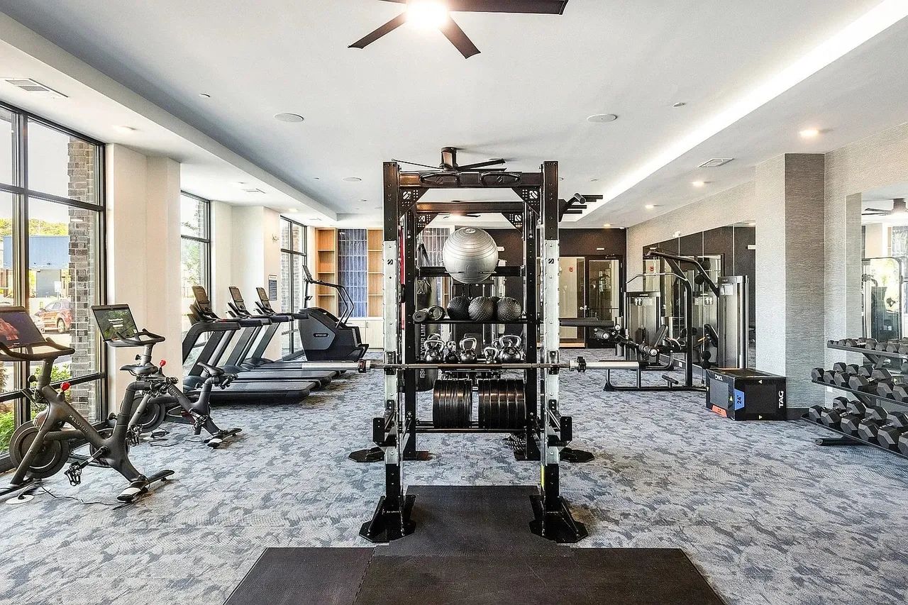 Une salle de sport équipée de tapis de course, d’une station pour les squats et d’haltères.