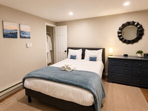 A bedroom with a bed, a dresser, a mirror, and two paintings on the wall. - Gunstock Chalet with Hot Tub & Massage Chair (Gilford)