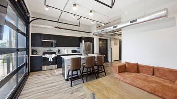 A modern kitchen with dark cabinets, stainless steel appliances, and a central island with bar stools.