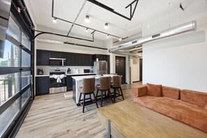 A modern kitchen with dark cabinets, stainless steel appliances, and a central island with bar stools. - Designer Downtown Fargo Loft · 2BR/1BA · Minutes to NDSU & Fargodome (Fargo)