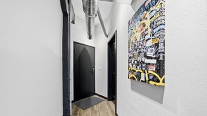 Un corridoio con una porta nera, un tappetino e un muro con un poster in stile graffito.
