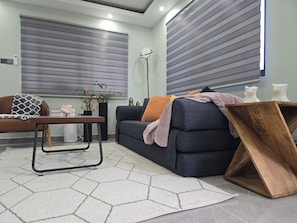 A modern living room with a sofa, a coffee table, and a floor lamp. - Boutique Styled 2BR Luxury Retreat Where Modern Comfort Meets a Relaxing Escape (Runaway Bay)