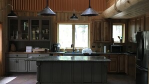 A spacious kitchen with a large island, wooden cabinets, and pendant lighting. - Perfect 2-bedroom cabin in soothing Custer for a relaxing stay. (Custer)