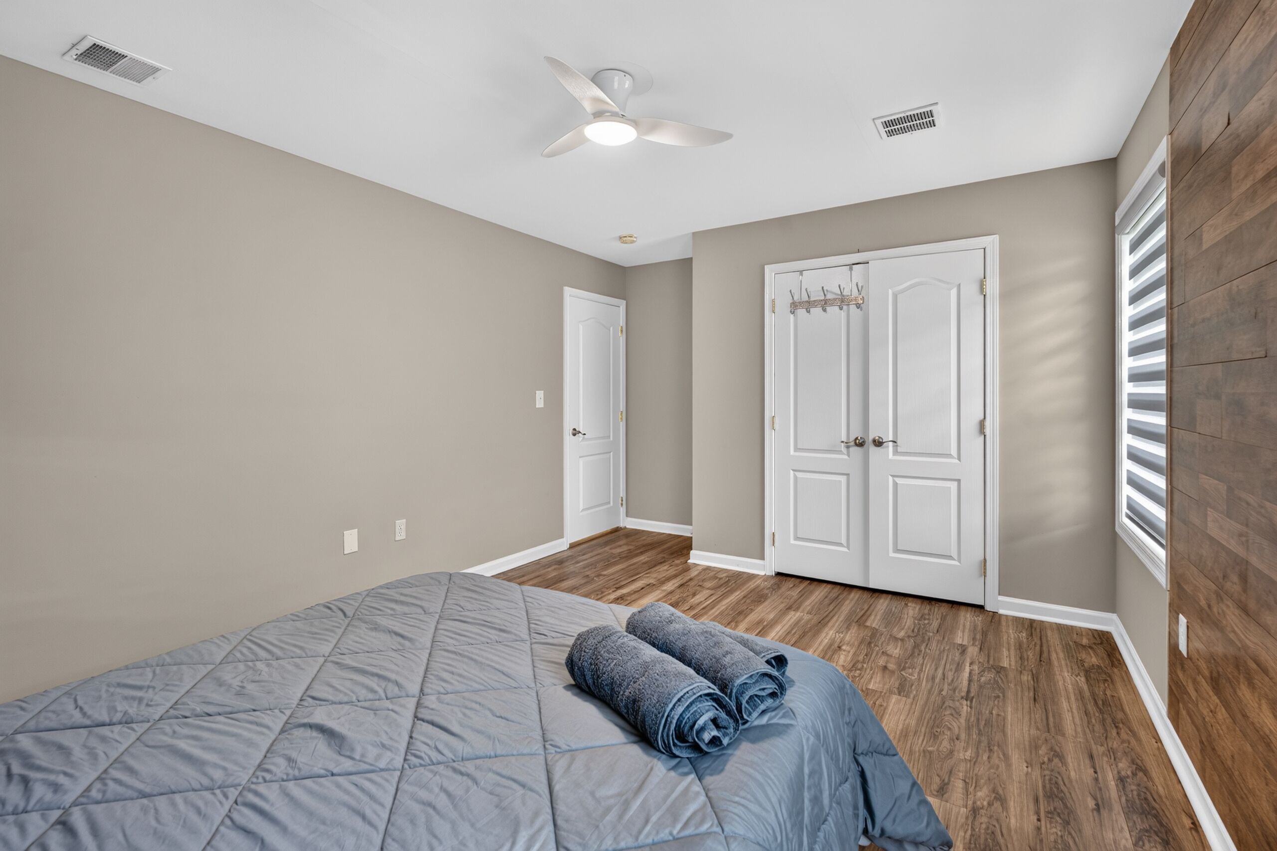 Une chambre à coucher avec un lit, un ventilateur de plafond et une armoire.