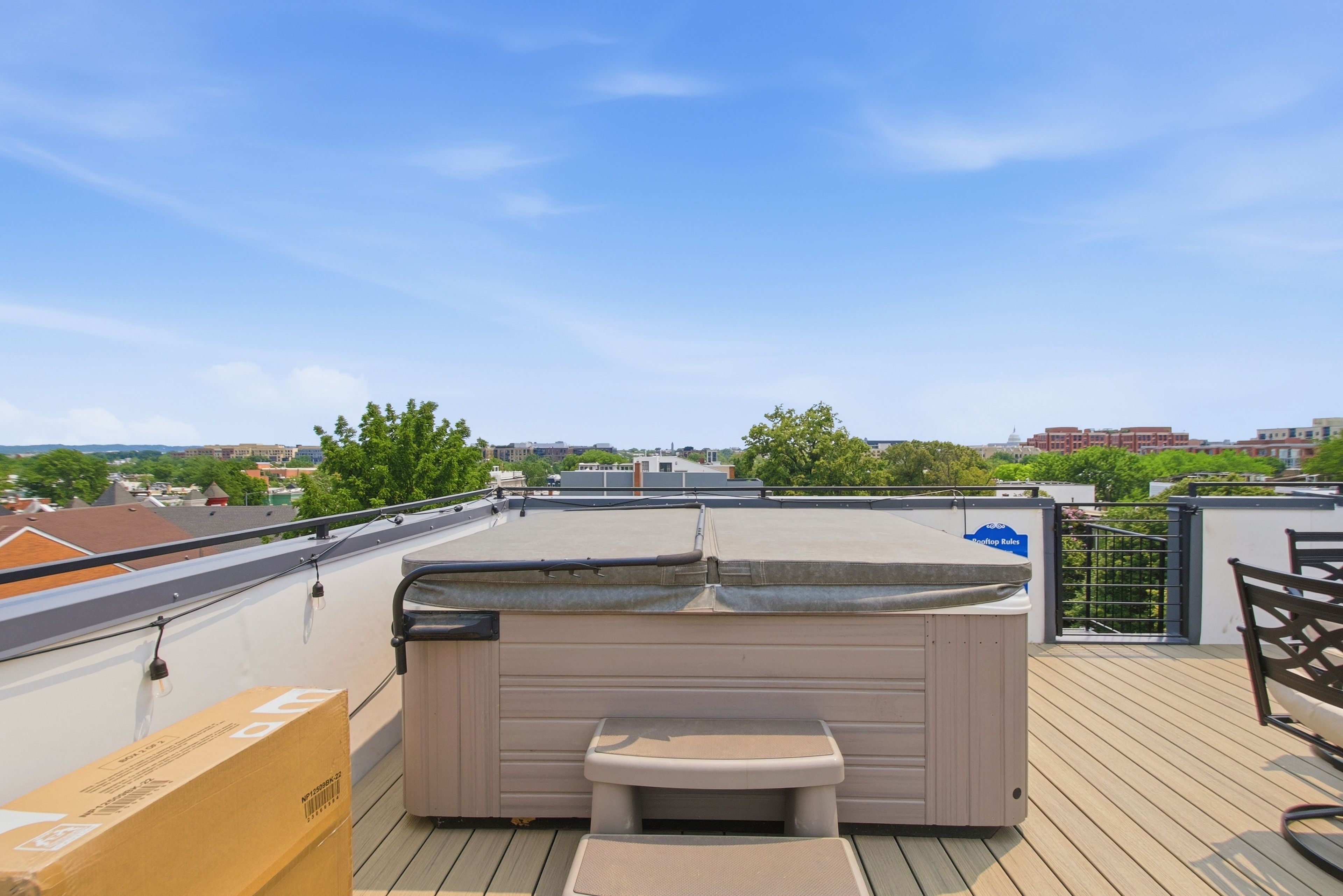 Eine Dachterrasse mit Whirlpool, Holzdeck und Blick auf die Stadt.