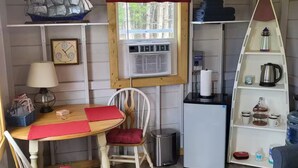 Un ambiente compatto con un tavolo da pranzo, sedie, un piccolo frigorifero e una scaffalatura.