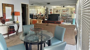 A modern living room with a glass coffee table, sofas, and a TV. - Ground level condo with a large enclosed patio, steps from the pool (Palm Springs)