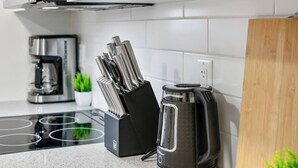 Et køkken med kaffemaskine, elkedel og et knivdisplay.