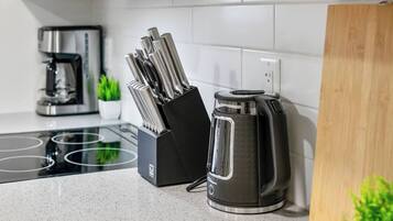 Une cuisine équipée d’une machine à café, d’une bouilloire et d’un bloc à couteaux.