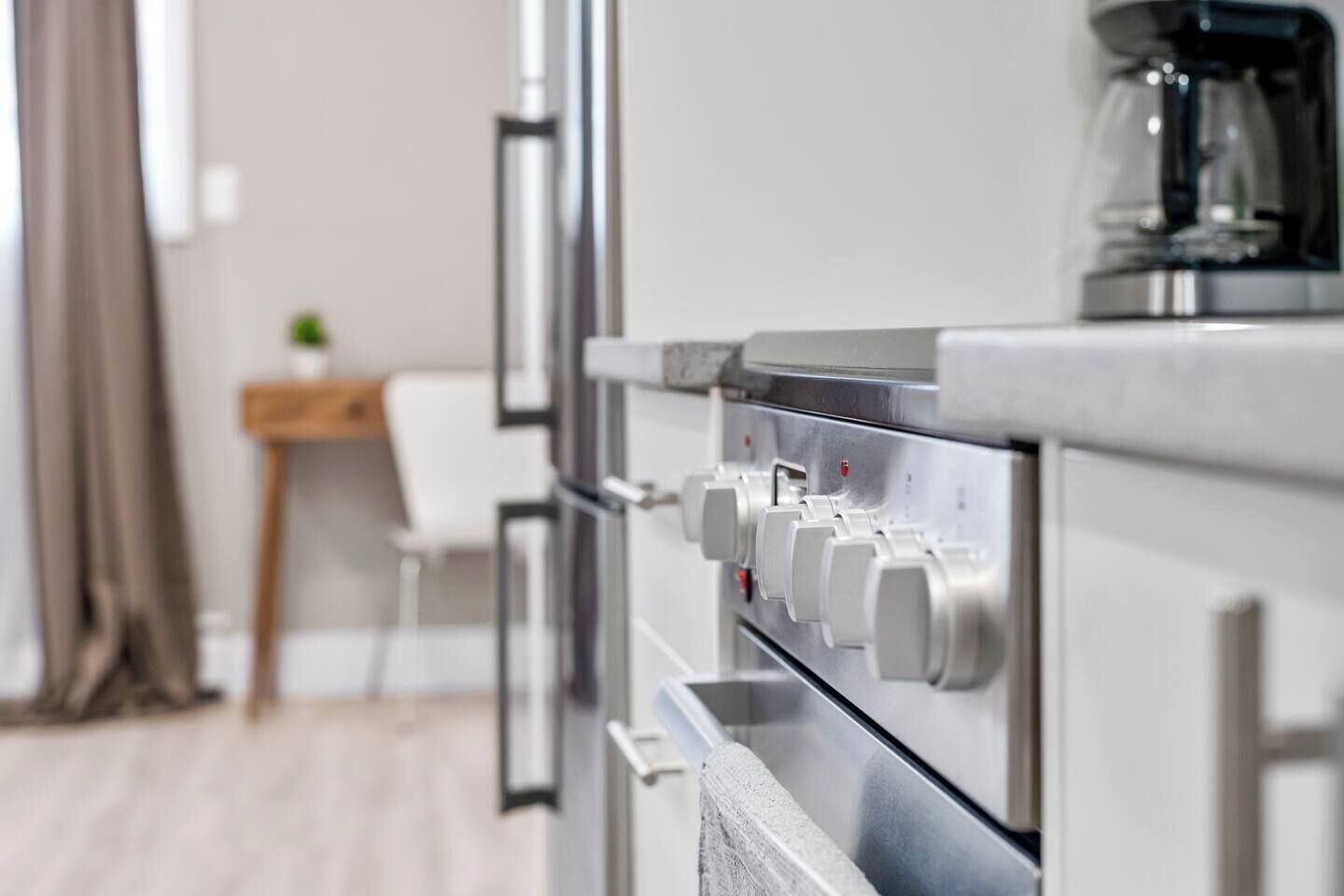 Une cuisine moderne équipée d’appareils électroménagers en acier inoxydable, d’une machine à café et d’une chaise blanche.