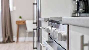 Une cuisine moderne équipée d’appareils électroménagers en acier inoxydable, d’une machine à café et d’une chaise blanche.