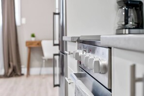 Eine moderne Küche mit Edelstahlgeräten, einer Kaffeemaschine und einem weißen Stuhl.