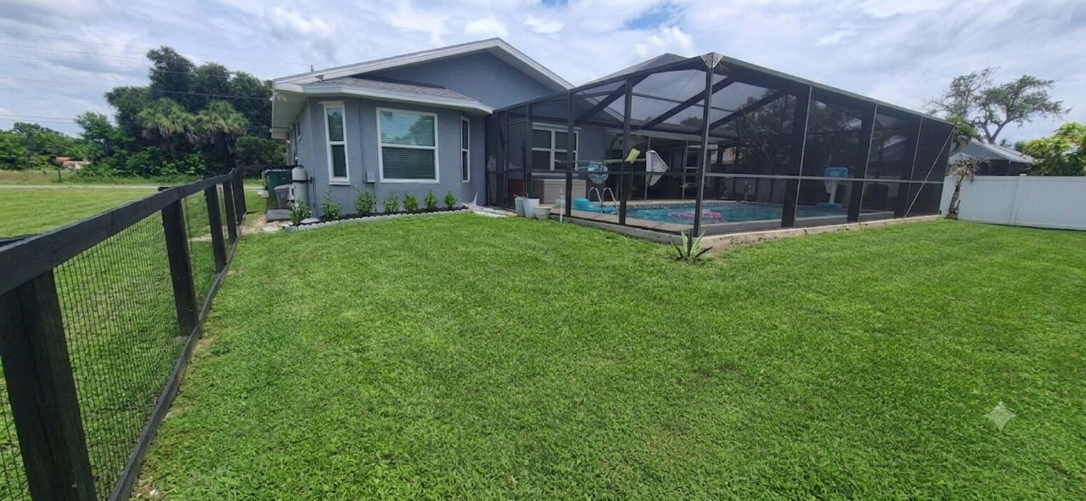 A residential property with a fenced backyard, a swimming pool, and a covered outdoor area.