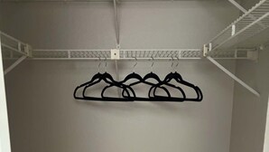Un placard avec une tringle en métal et des crochets pour suspendre les vêtements.