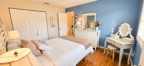 Ein Schlafzimmer mit Bett, Kommode, Schminktisch und Lampe.