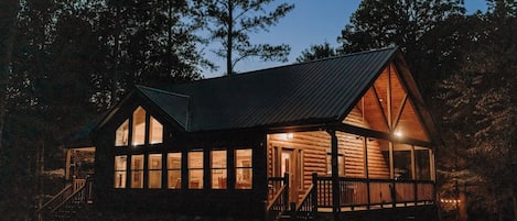 Une cabane dotée d’une véranda, de grandes fenêtres et d’un escalier menant à l’entrée.