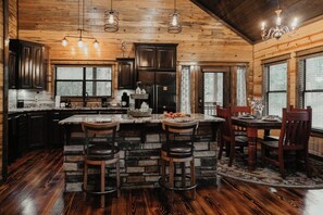 Una cucina con isola in pietra, pensili in legno scuro e un'ampia finestra.