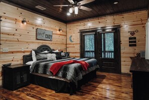 Una camera accogliente con soffitto in legno, un letto con coperta rossa e un comodino.