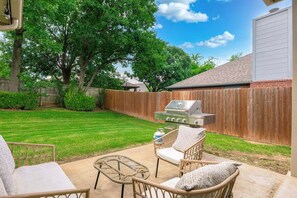 A backyard with a barbecue grill, wicker furniture, and a wooden fence. - Casa Joya @ Jenks Spain Ranch/Five Oaks (Jenks)