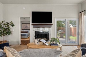 Ein Wohnzimmer mit Kamin, Fernseher und einer Schiebetür zum Außenbereich.
