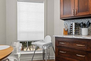 A kitchen with a window, a high chair, and wooden cabinets. - Casa Joya @ Jenks Spain Ranch/Five Oaks (Jenks)