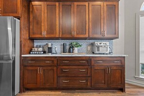 Eine Küche mit Holzausstattung, einem Edelstahlkühlschrank, einer Mikrowelle und einer Kaffeemaschine.