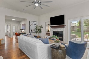 A living room with a sofa, a fireplace, a television, and a view of the outdoors. - Casa Joya @ Jenks Spain Ranch/Five Oaks (Jenks)