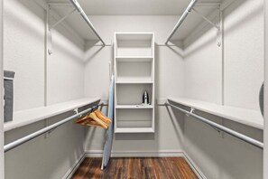 Ein begehbarer Kleiderschrank mit weißen Regalen und einer Kleiderstange.