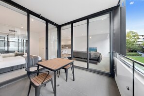 Un intérieur moderne avec un balcon, un coin repas comprenant une table et des chaises, et un salon avec un canapé et une table basse.