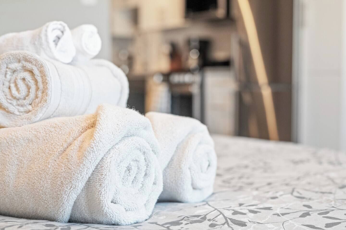 Des serviettes soigneusement pliées sont posées sur un lit recouvert d’une couvre-lit à motifs.