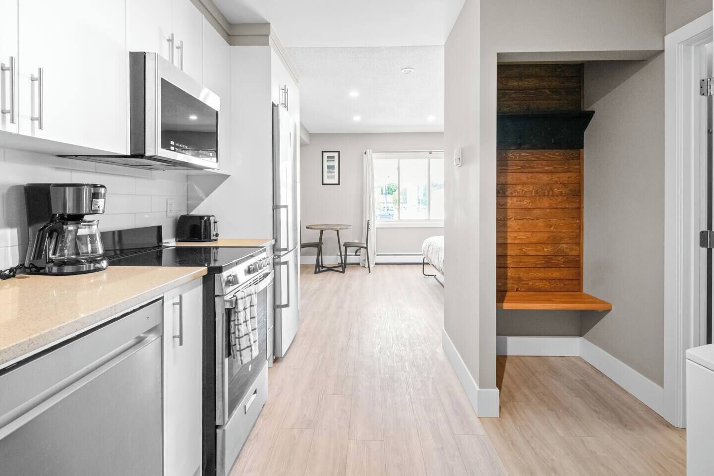 Una cocina moderna con electrodomésticos de acero inoxidable, una cafetera y un comedor con mesa y sillas.