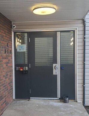 A black sliding door with a security keypad and a peephole. - Boutique-Style Studio Unit (Edmonton)