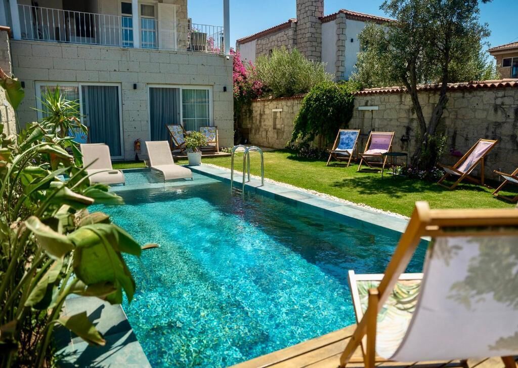 Una piscina al aire libre, sombrillas, sillones reclinables de piscina