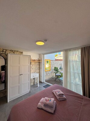 A bedroom with a bed, a desk, a wardrobe, and a balcony with a view. - Noesta Alaçatı (Çeşme)