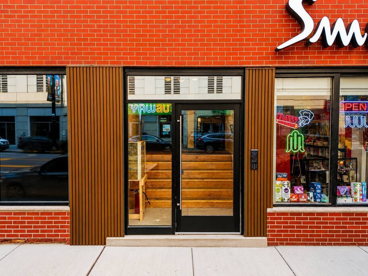 A storefront with a brick facade, a large glass window, and a neon sign.